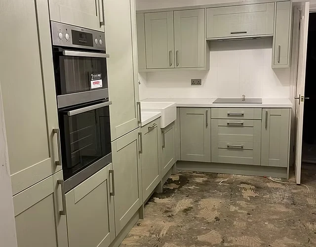 Newly fitted sage green kitchen cabinetry and integrated ovens, part of a Crystal Clear kitchen installation